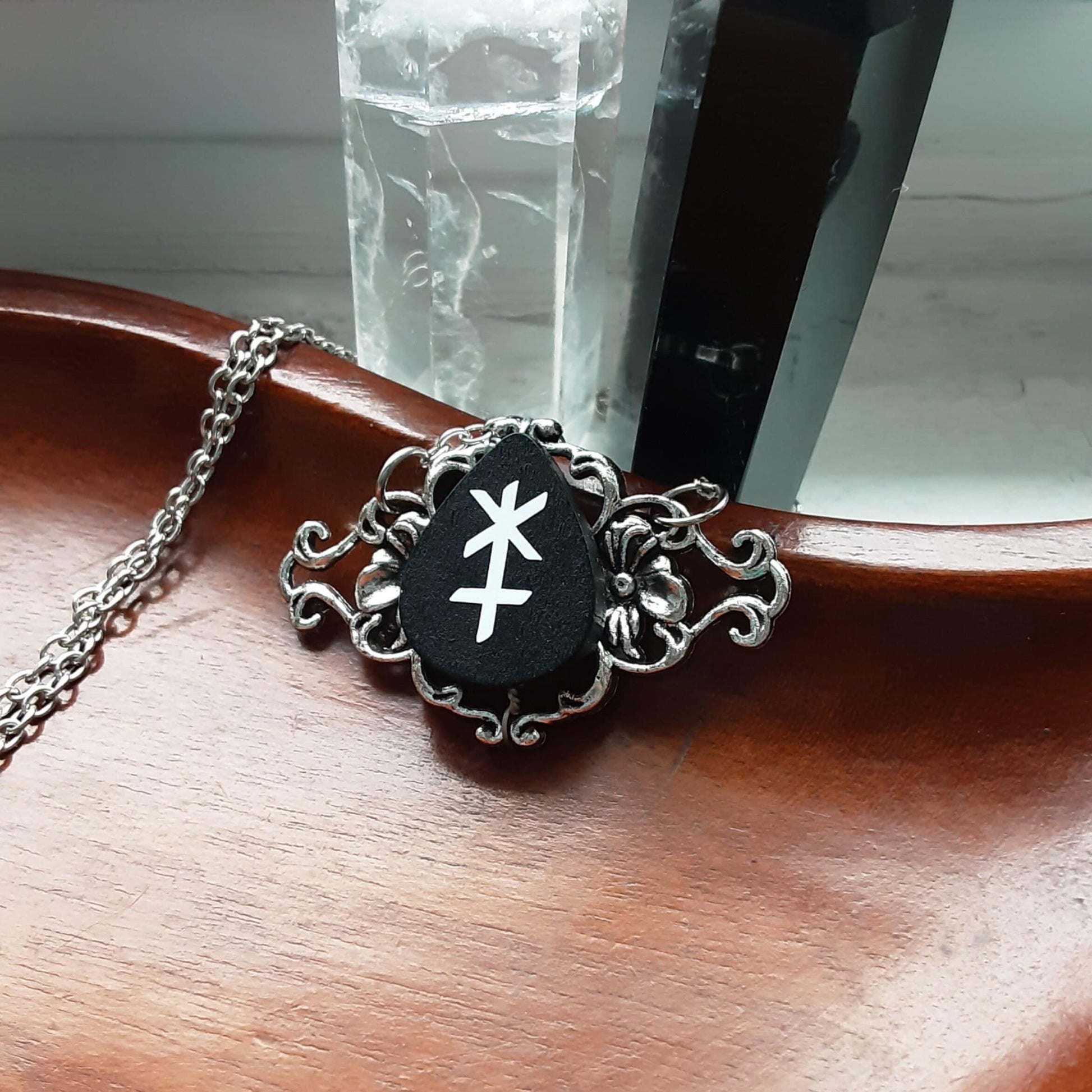 Hera Astrology Symbol Necklace on Wooden Plate with Clear Quartz and Obsidian Crystals in the background