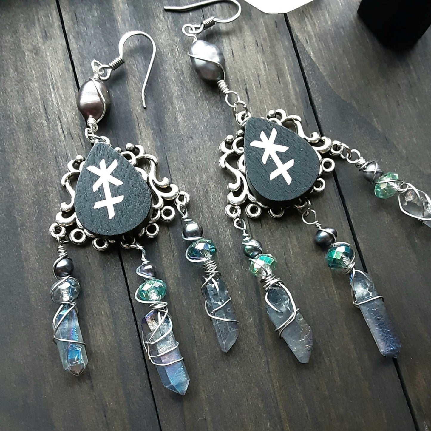 Hera Astrology symbol earrings with peacock pearls and Quartz shards on wooden background