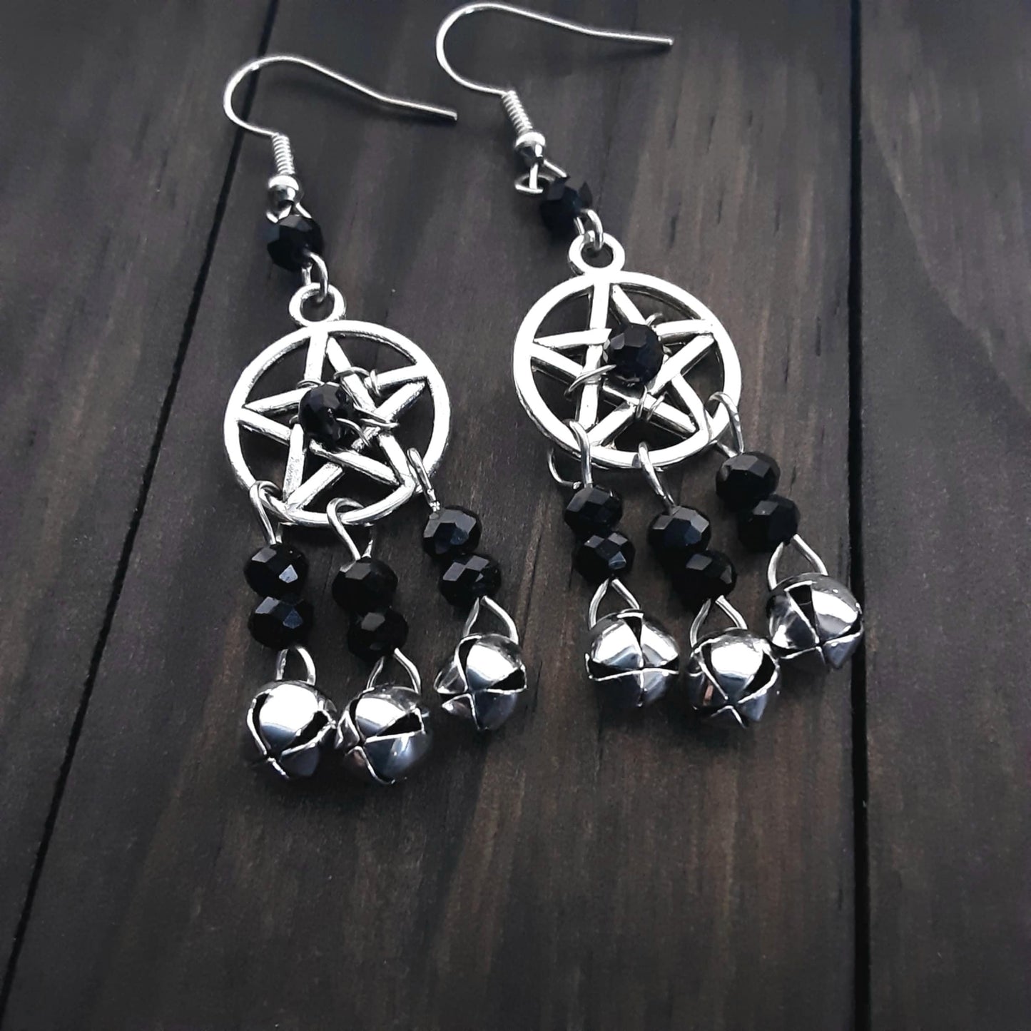 Pentacle earrings with black crystals and bells on wooden background